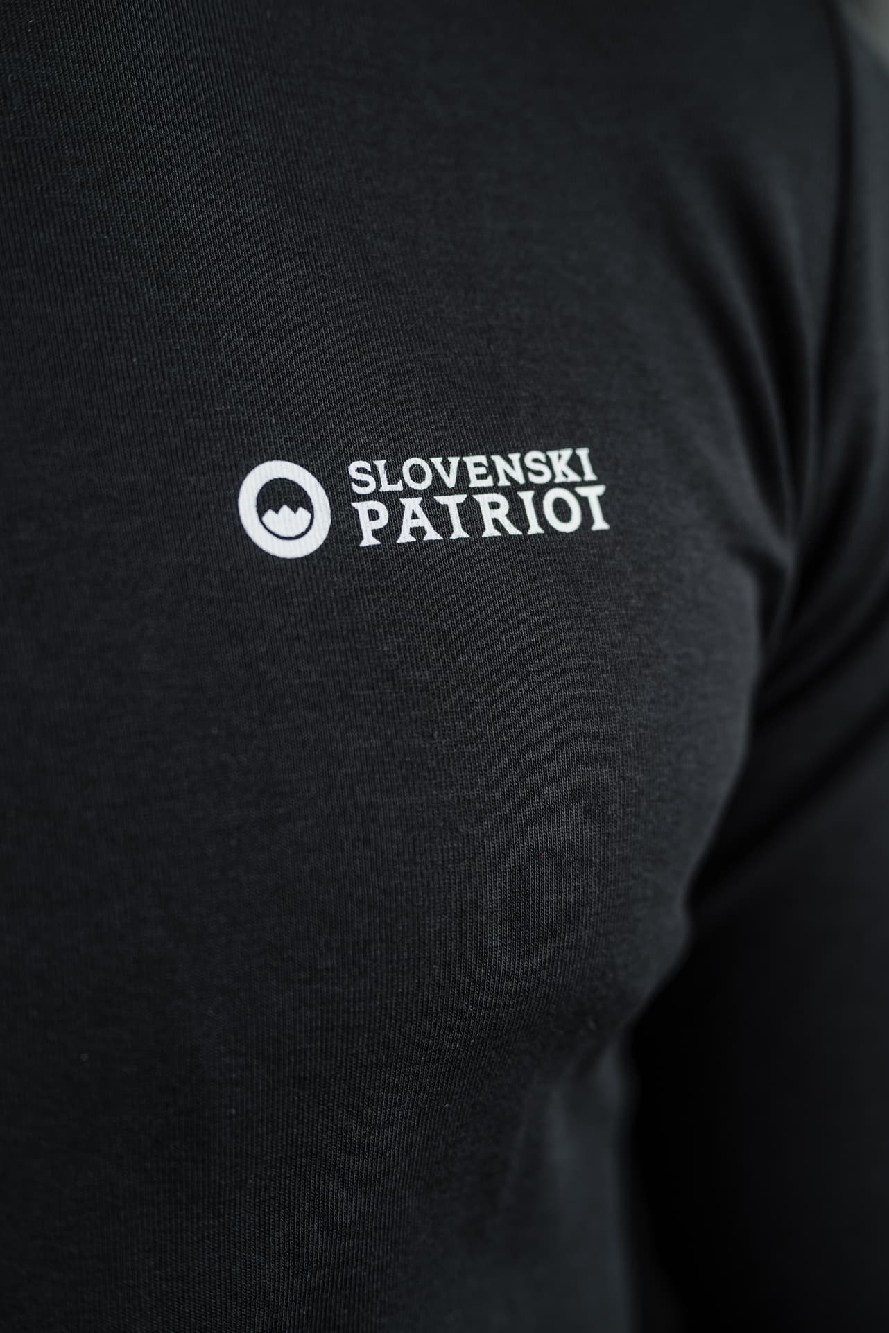 Detajl črne 100% bombažne majice z dolgimi rokavi Tech Pro znamke Slovenski Patriot, z logotipom na prsnem delu, narejeno v Sloveniji.