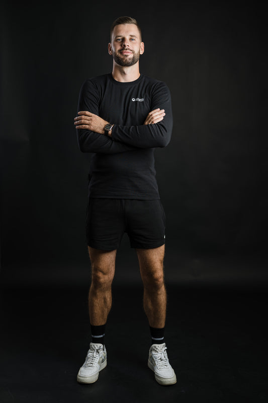 Moški nosi črne kratke hlače MOVE znamke Slovenski Patriot, narejene iz bombaža in zasnovane za udobno gibanje, narejene v Sloveniji.