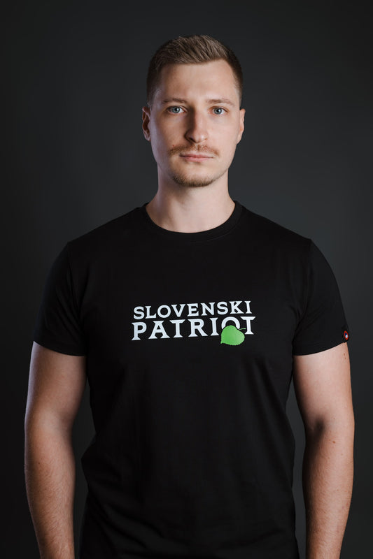 Moški nosi črno bombažno majico z napisom Slovenski Patriot in zelenim lipovim listom, narejeno v Sloveniji.