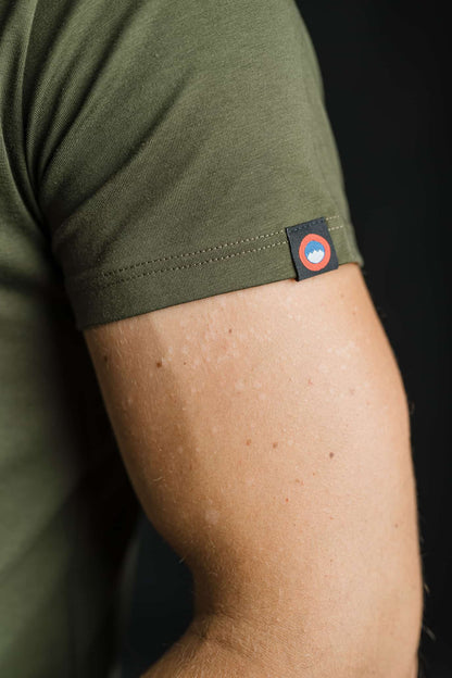 Bližnji posnetek rokava olivne majice FIT znamke Slovenski Patriot z všitim logotipom v rdeče-modri barvi, ki poudarja pozornost do detajlov in slovensko identiteto.