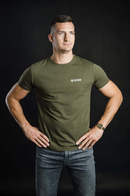 Moški v olivno zeleni majici FIT znamke Slovenski Patriot z rokami na bokih, ki poudarja prileganje majice, narejene v Sloveniji.