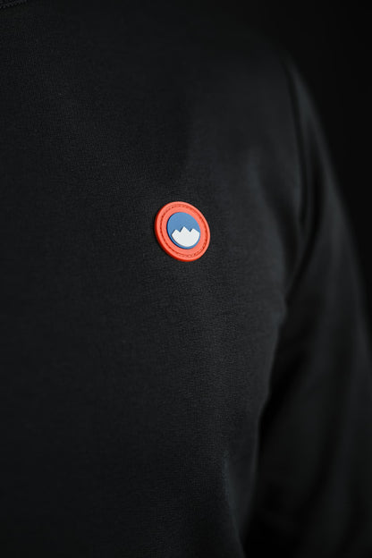 Detajl rdeče-modrega logotipa Slovenski Patriot na črnem puloverju Patriot Crew, narejenega v Sloveniji iz kakovostnega bombaža.